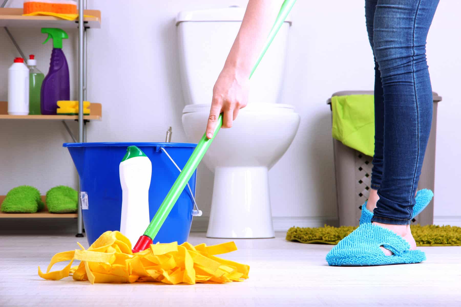 woman with orange mop cleaning bathroom floors