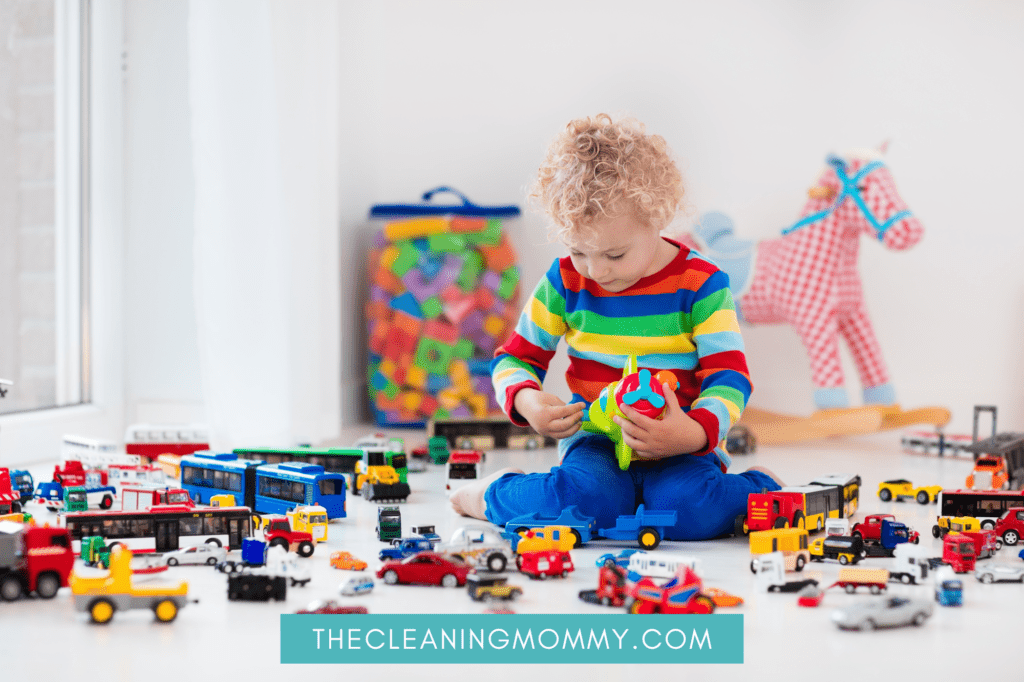 Toddler in colorful sweater playing with many toys on floor