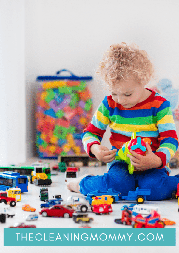 Toddler in colorful sweater playing with many toys on floor