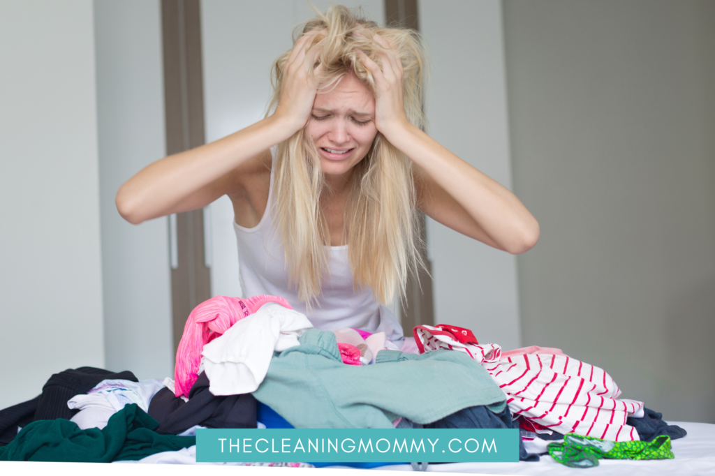 Blond woman getting stressed over piles of clothes.