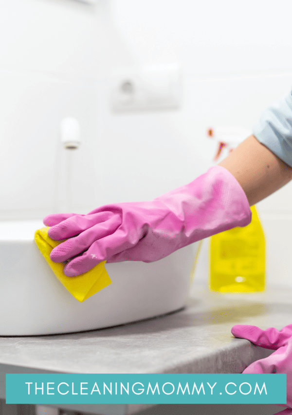 Mom cleaning bathroom sink with pink gloves