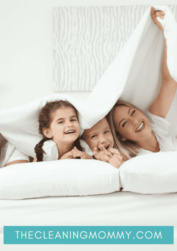 Mom, dad, young son and daughter cuddling under white duvet