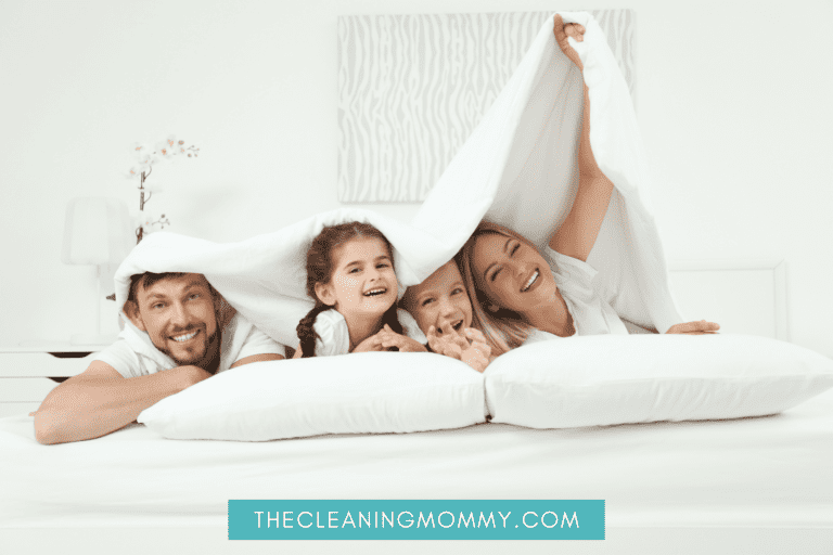 Mom, dad, young son and daughter cuddling under white duvet