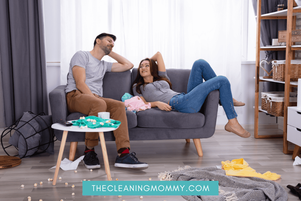 Husband and wife sitting on couch surrounded by clutter