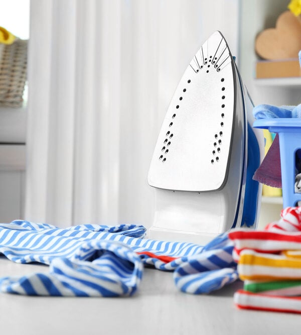 Iron sitting beside a pile of laundry